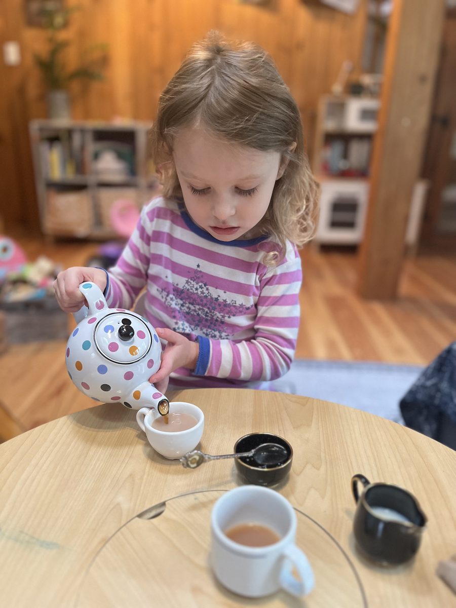 A little girl pouring tea from a polka-dot teapot